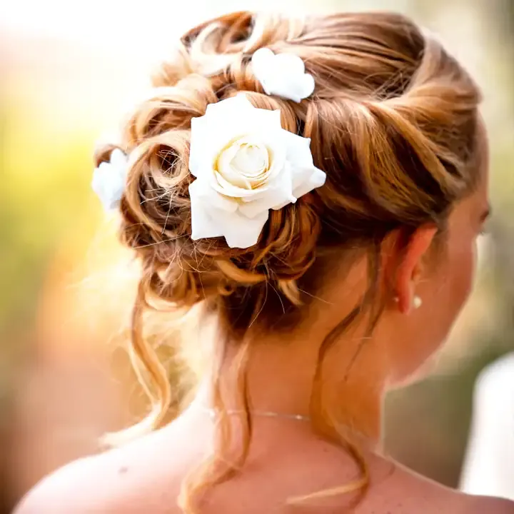 Curly bridal updo decorated with white roses, seen from behind