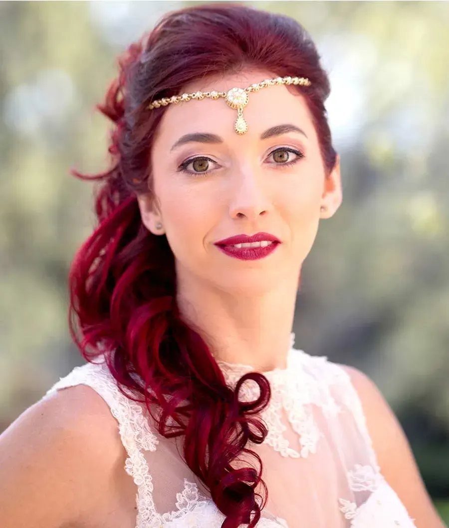 Bride with long curly red hair swept over one shoulder, gold forehead jewel