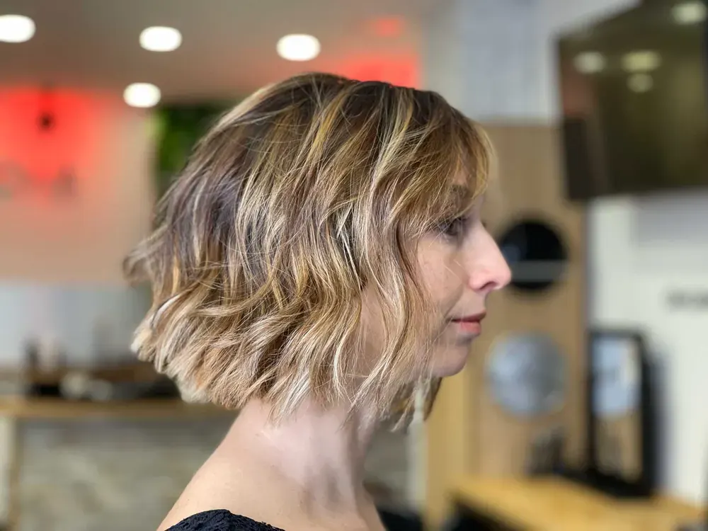 Soft wavy bob with highlights, side view in the salon